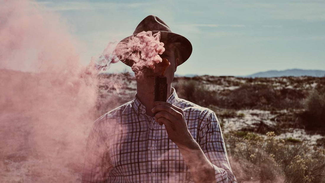 Man standing in a field, blowing vapor