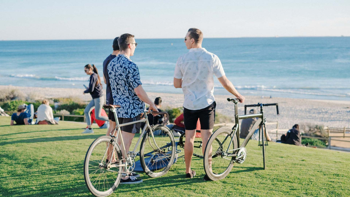 group of friends with bikes on a grass field overlooking an ocean