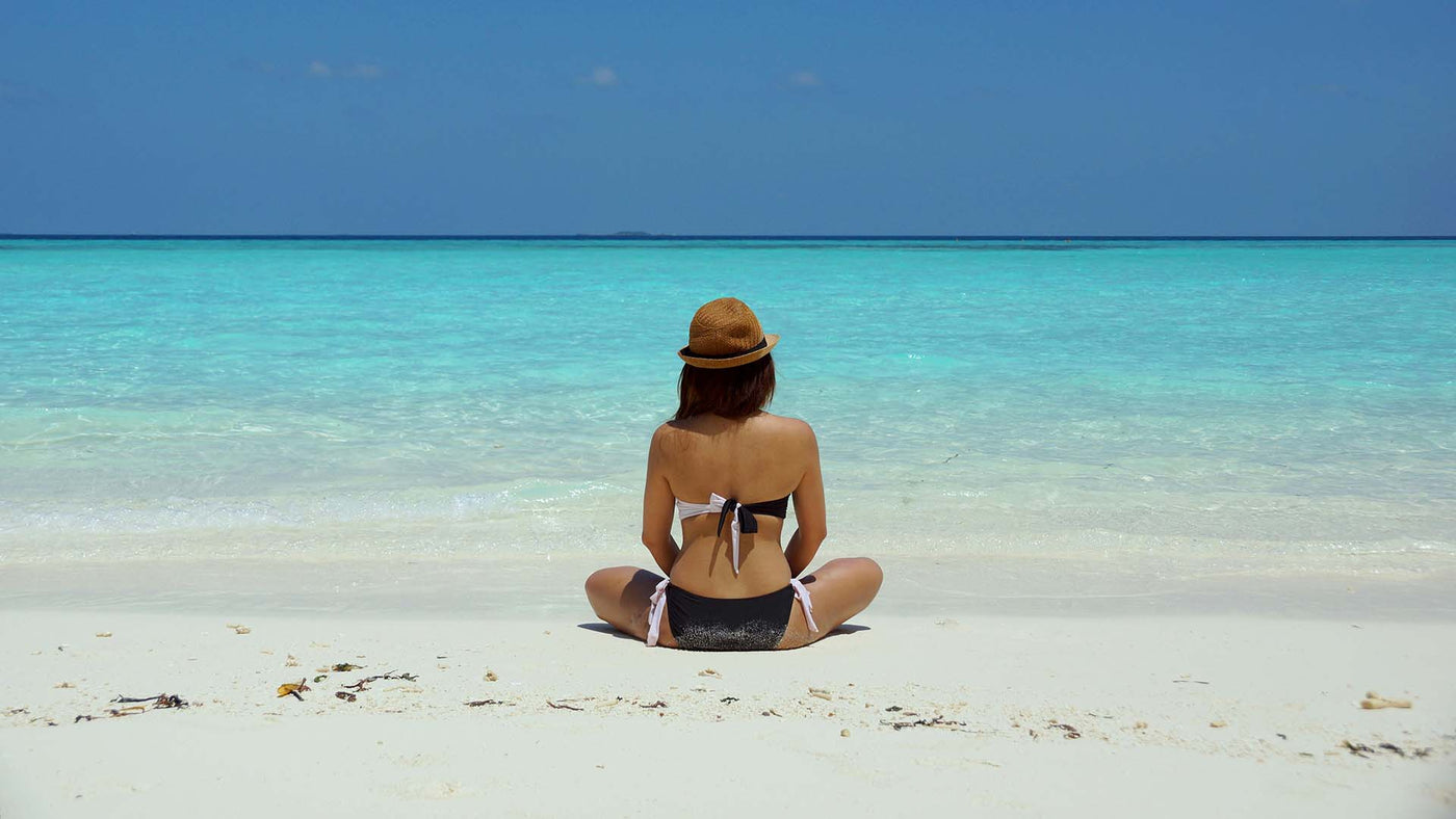 woman sitting on a sand facing the blue-green beach