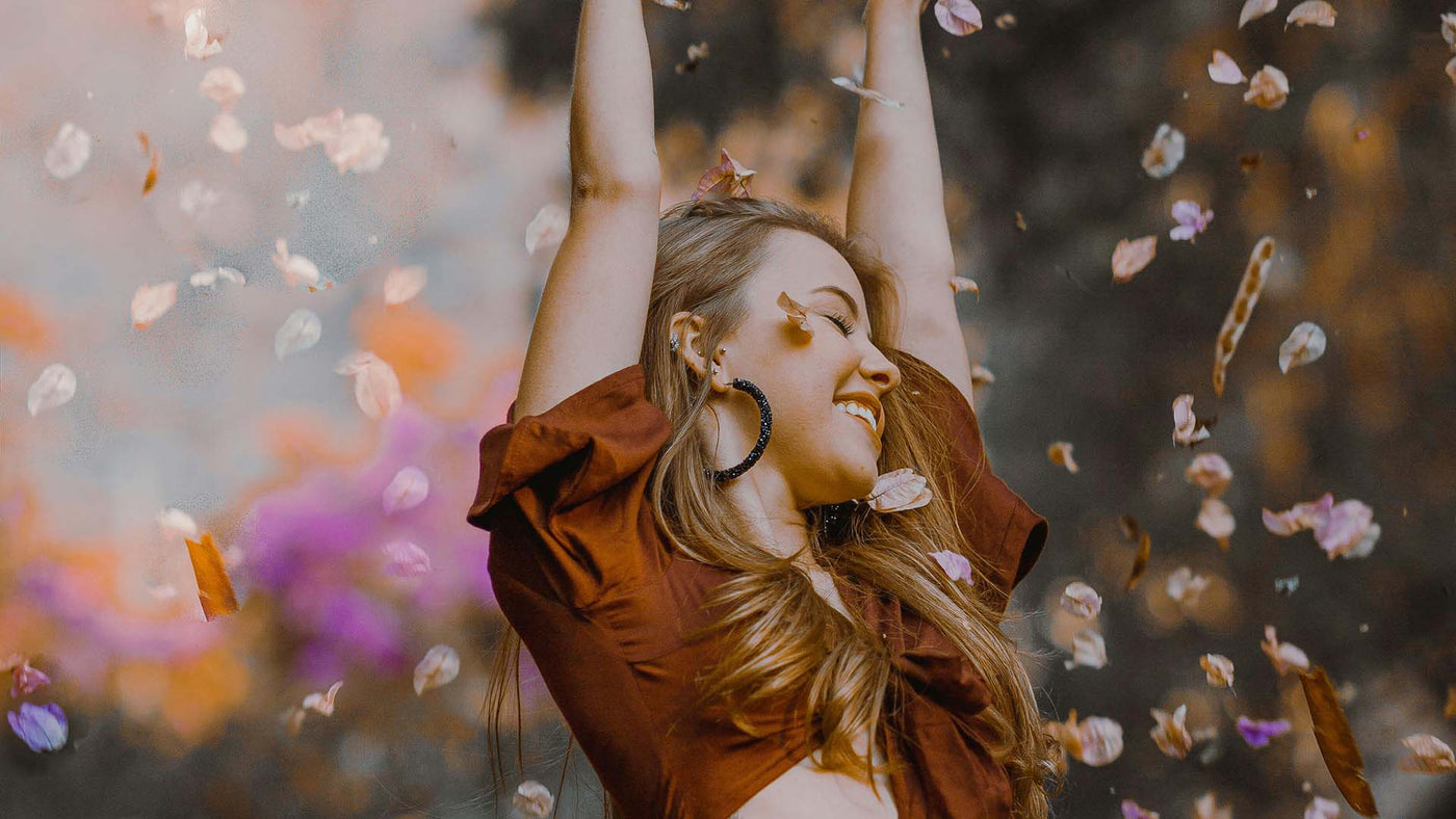 girl smiling with arms outstretched, flower petals falling from above