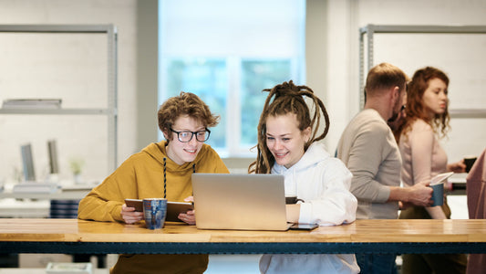 Two women smiling while looking at a laptop.