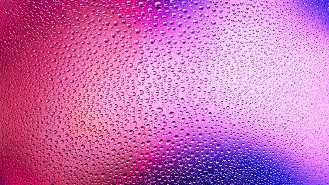 Water droplets on glass with a blue, pink and purple background
