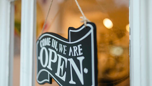 black and white open signage hanging on a store's glass window