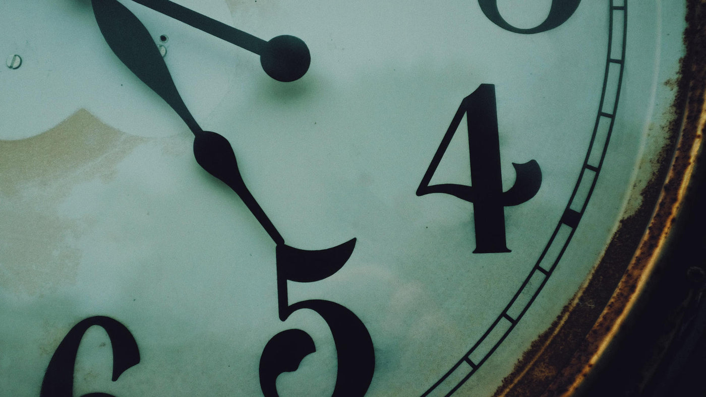 A close-up shot of an old clock with its hands on four twenty-five.