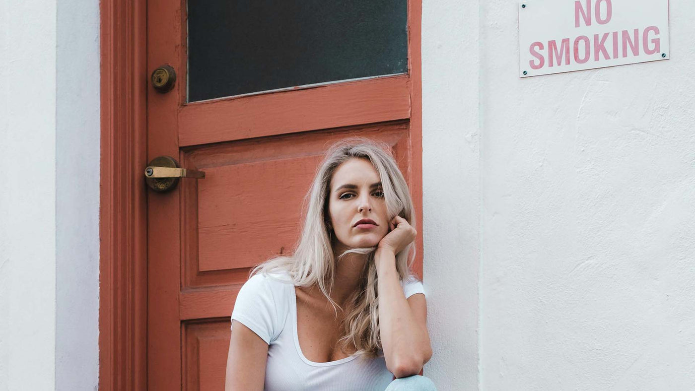 Woman sitting next to a No Smoking sign