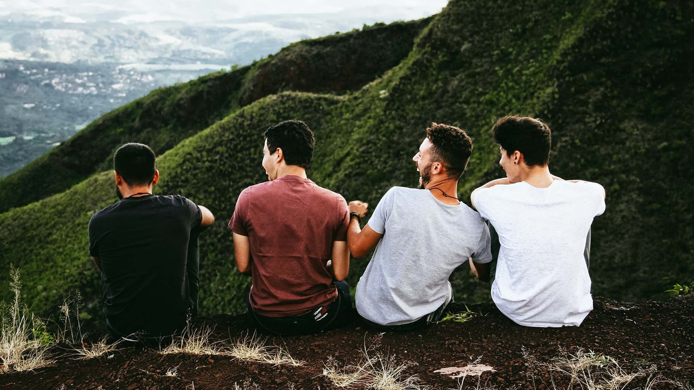 group of men happily sitting on a mountain trail
