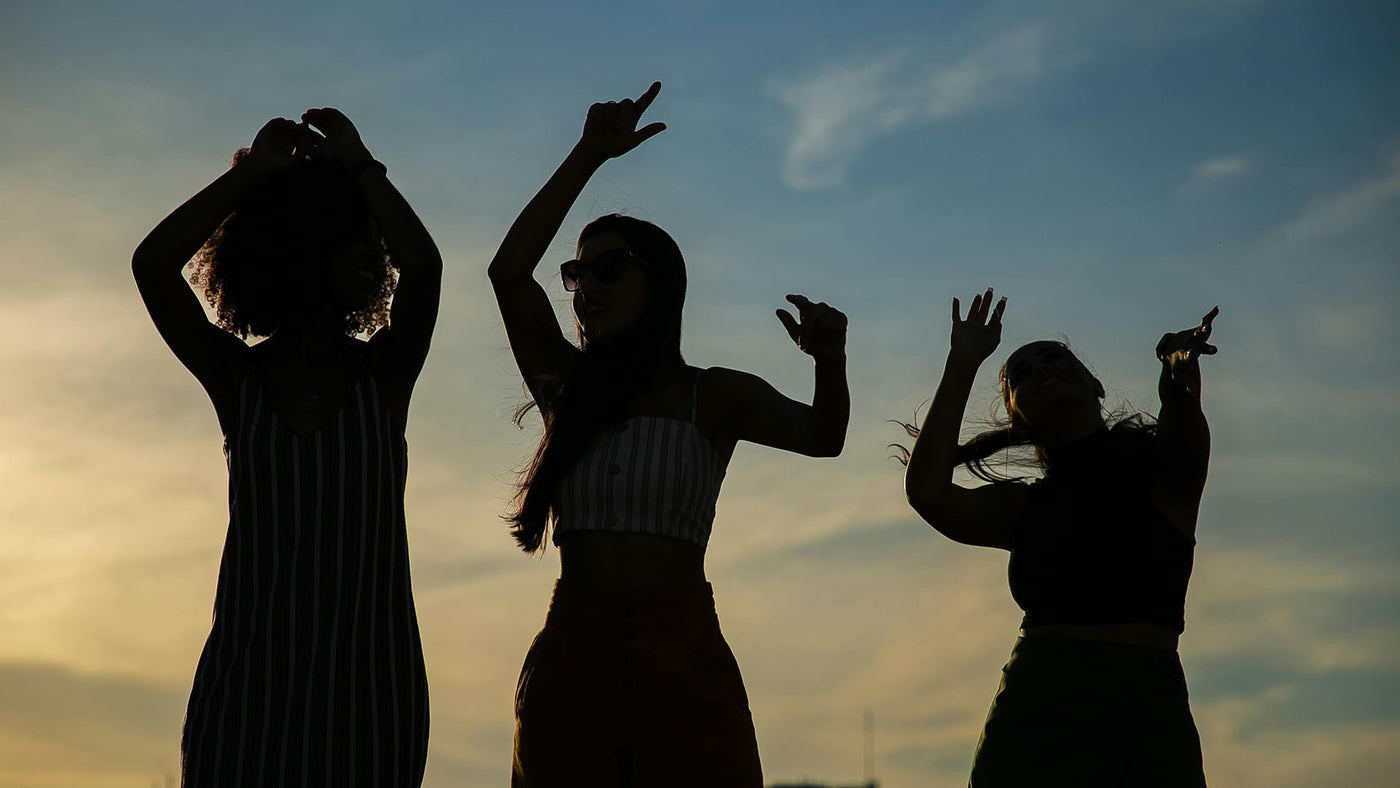 Three women dancing in silhouette