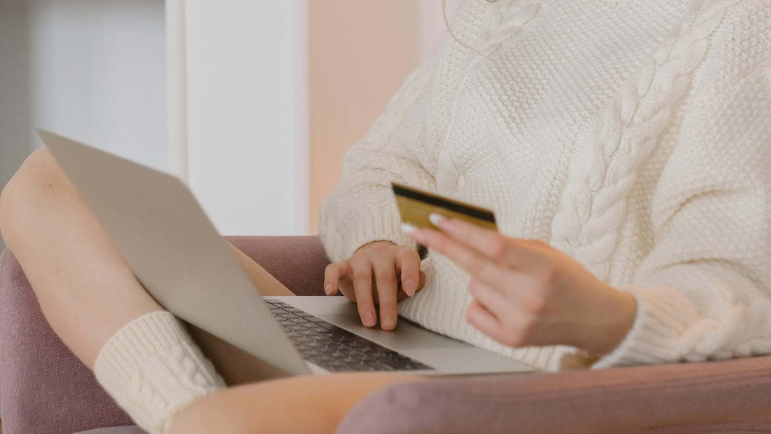 Person using a laptop and holding a credit card