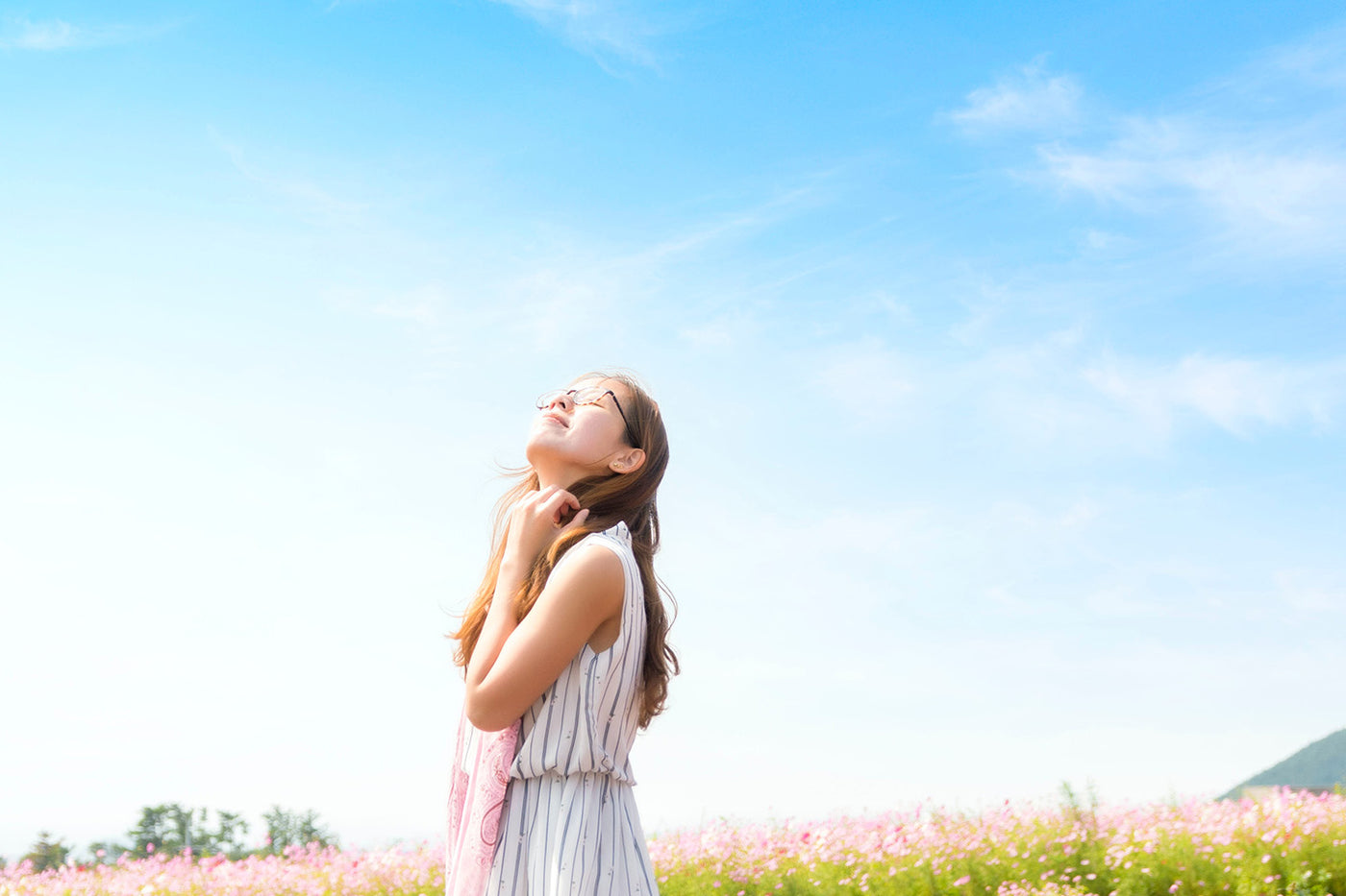 woman smelling the air while looking up the blue sky