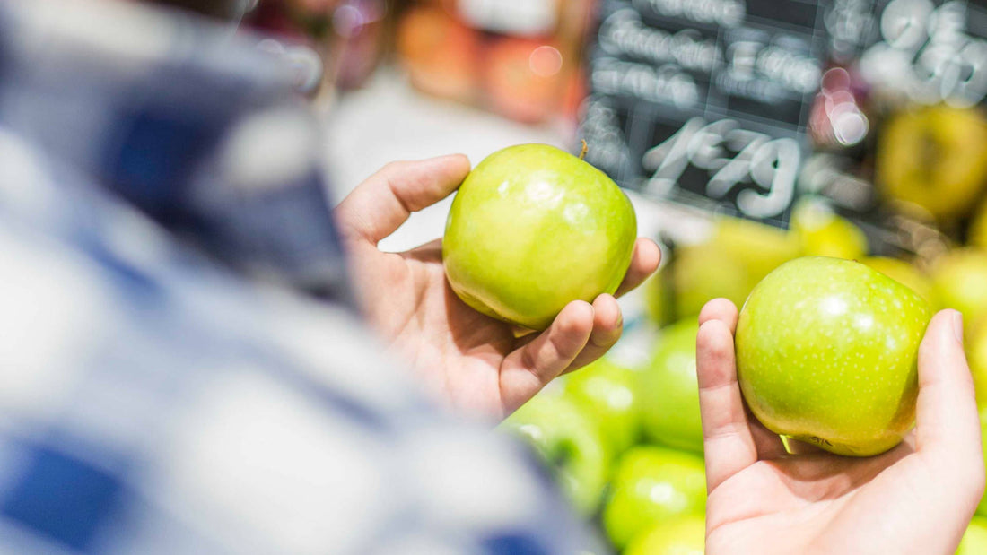 A person comparing two green apples side by side.