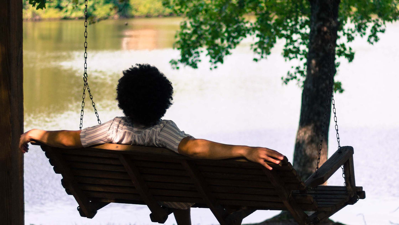 Person sitting on a bench swing overlooking water