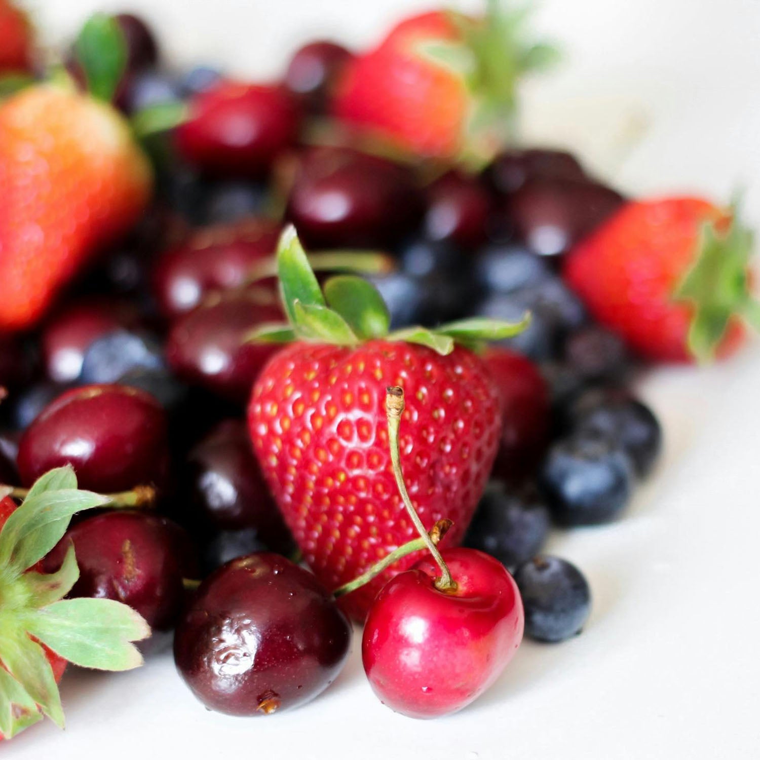 close-up of strawberries, cherries, and blueberries on white table