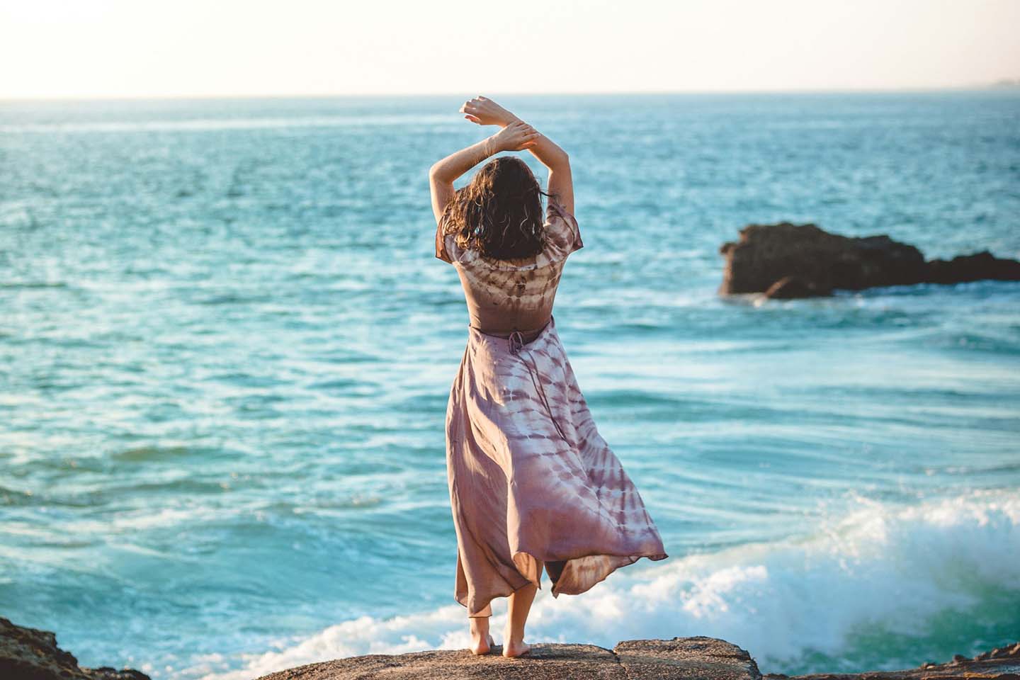 woman standing on a rock looking at the ocean