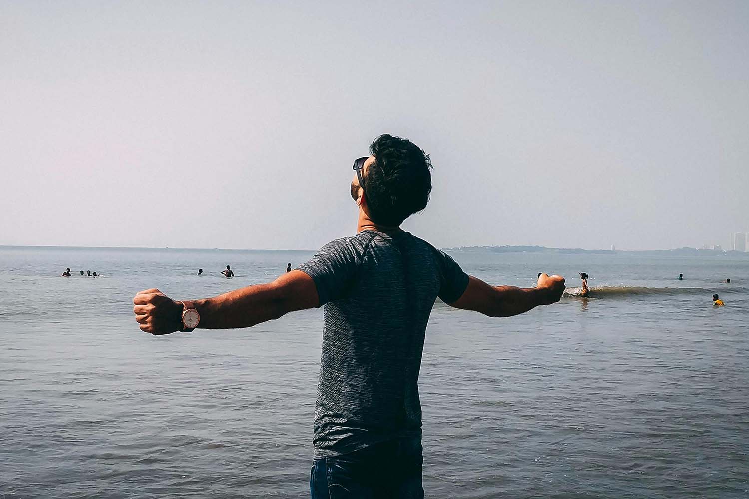 Man facing the sea with his arms outstretched