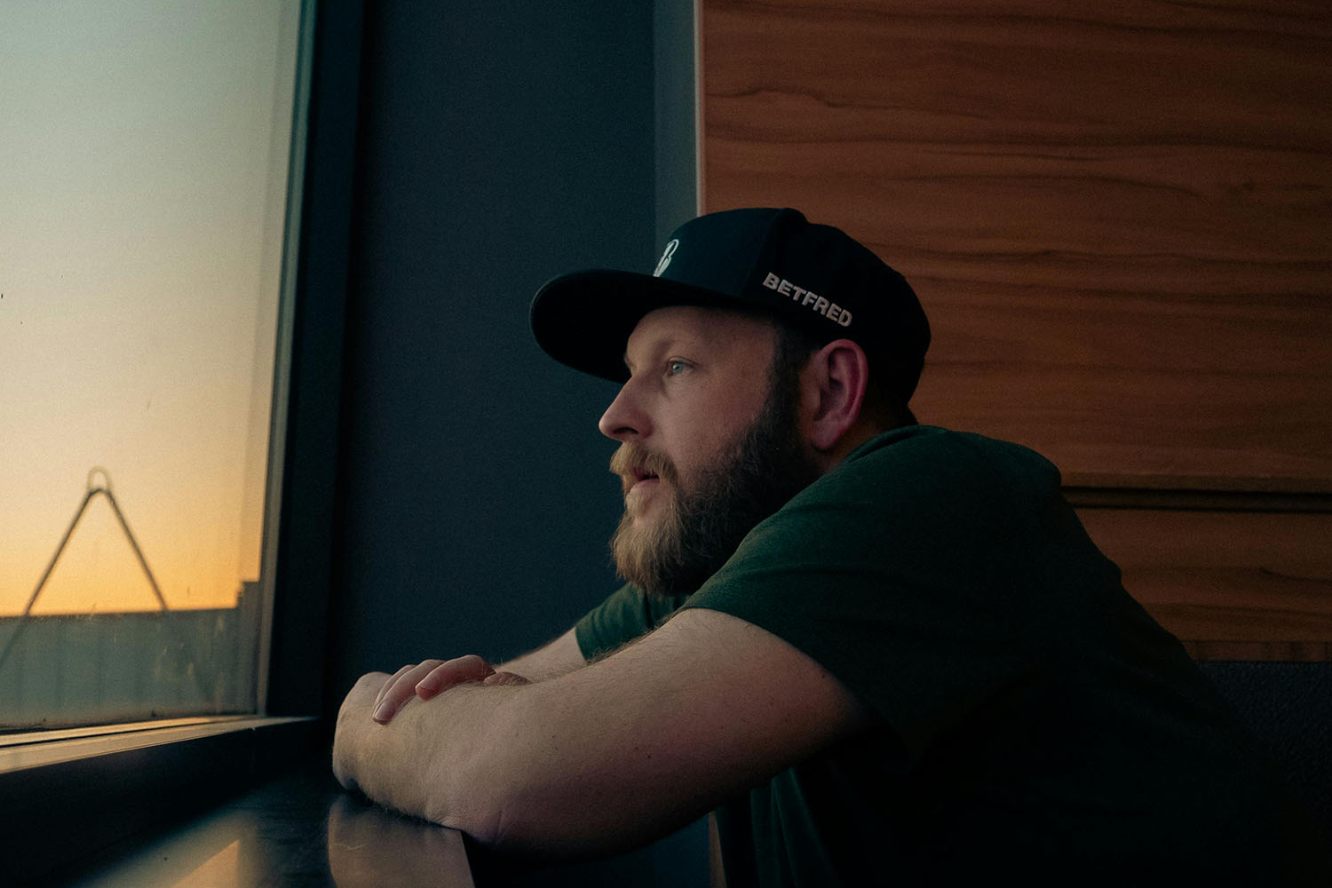 A man looking outside while leaning on windowsill