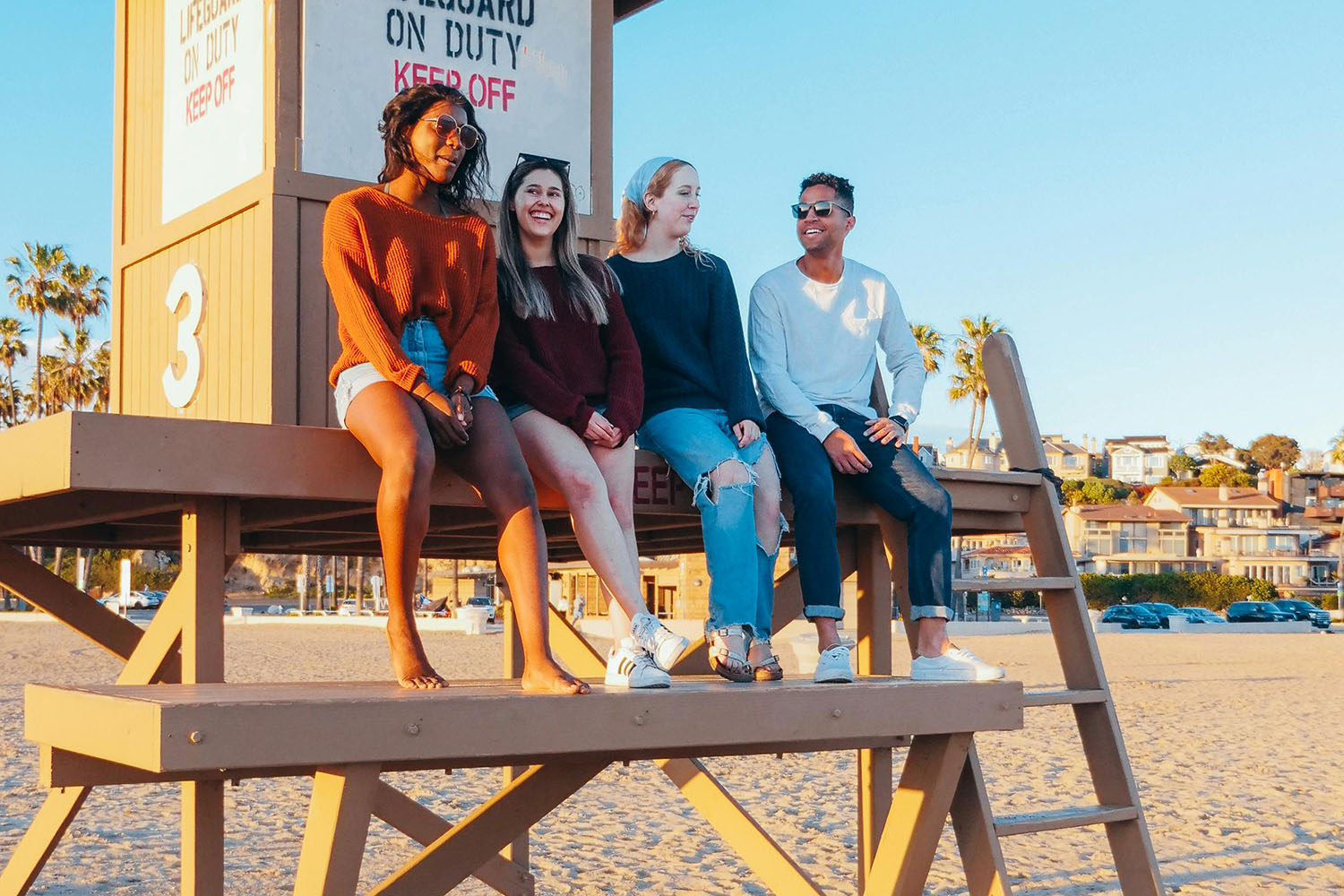 Group of friends sitting on a lifeguard tower in the beach