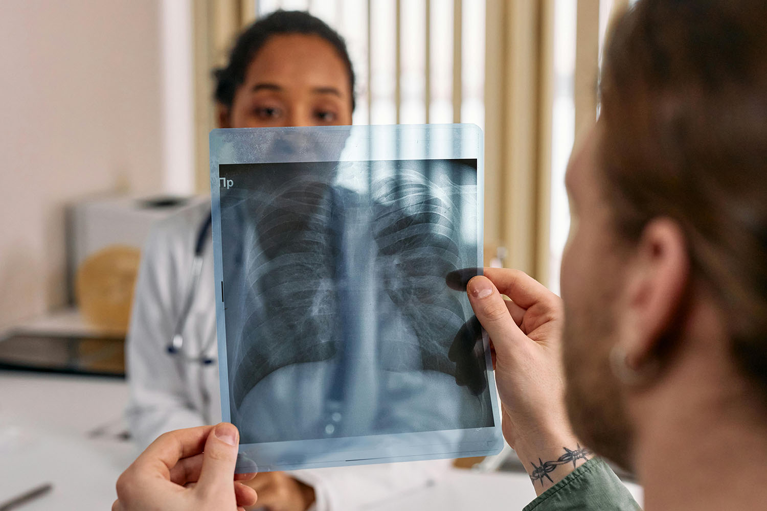 Patient holding a lung x-ray result in front of a doctor