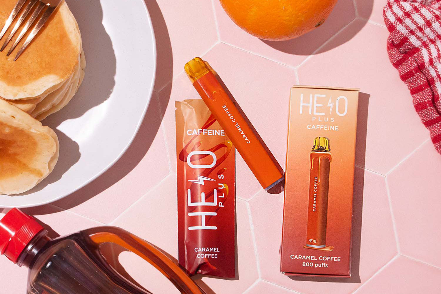 HELO Caramel Coffee vape on a breakfast table with syrup, pancakes, and an orange