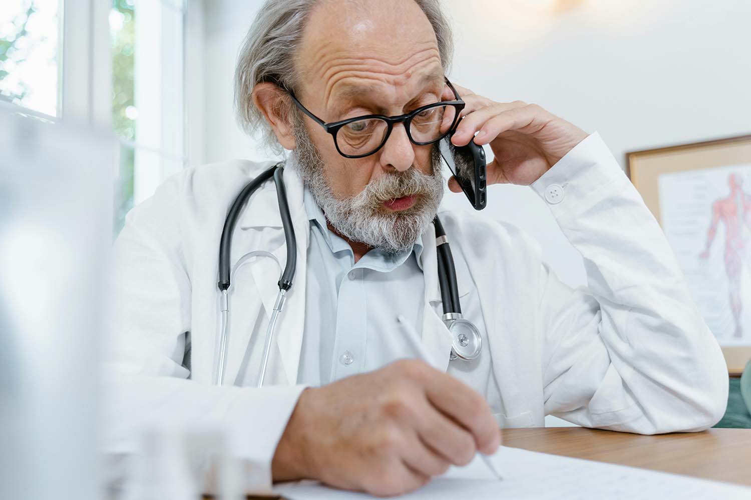 Doctor on the phone taking notes on a piece of paper