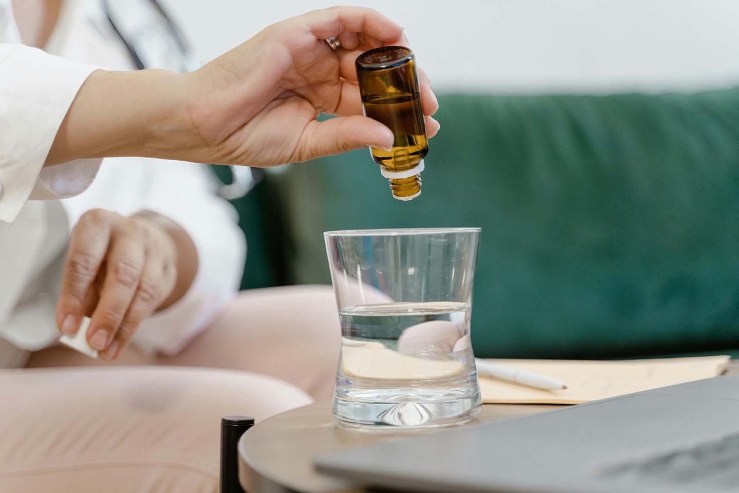 Person pouring liquid from an amber dropper into a glass of water