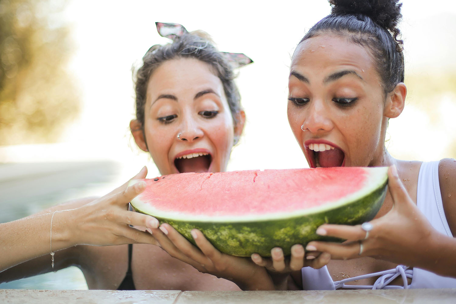 Two women biting into a large slice of watermelon