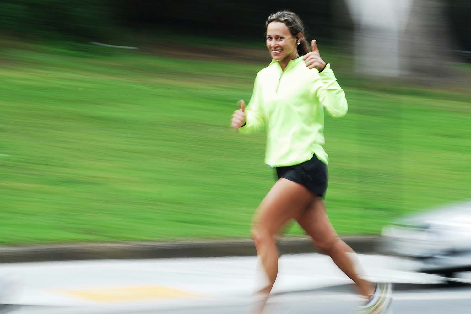 Woman running and giving a thumbs-up sign