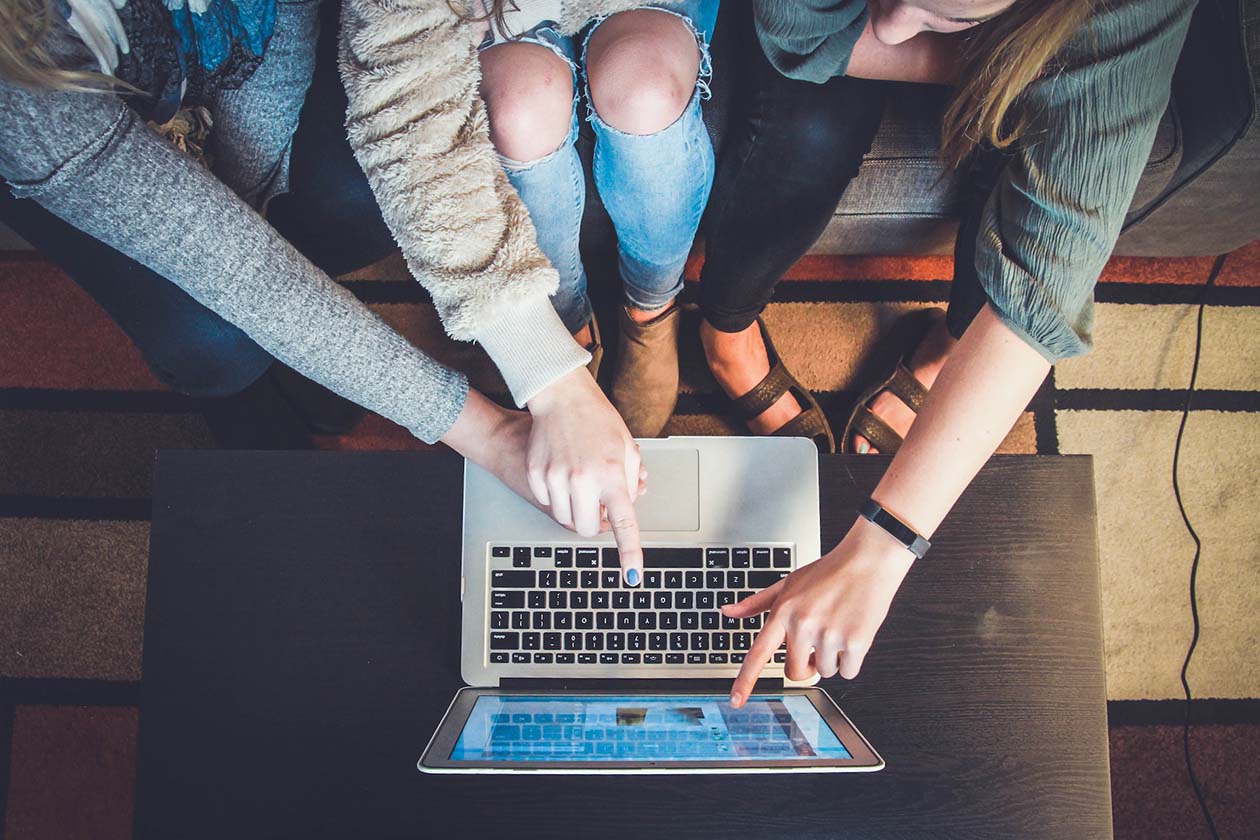 three women looking and pointing at a computer screen