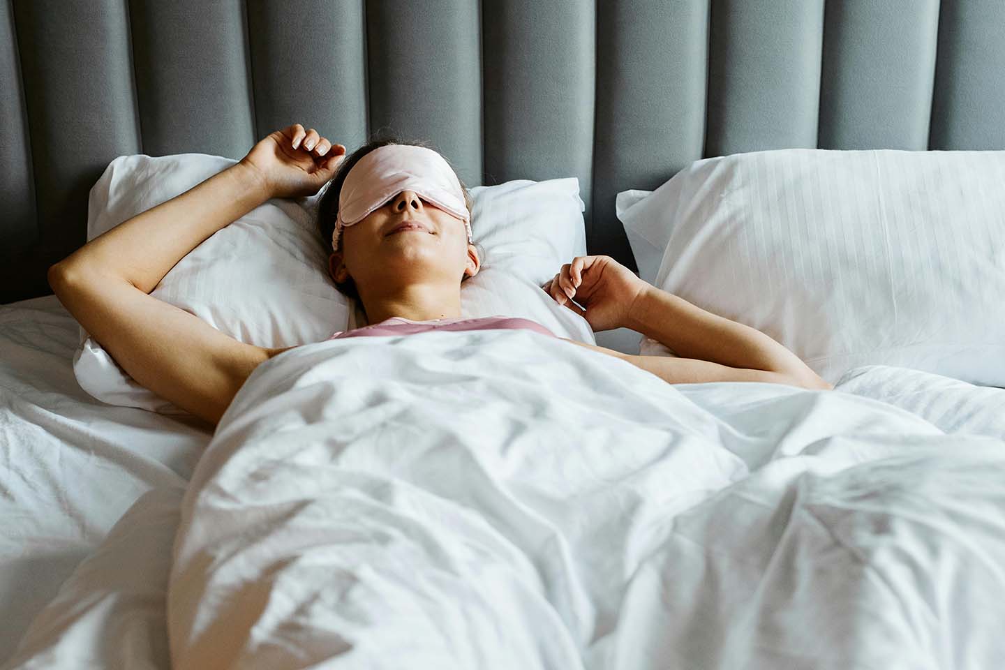 person sleeping in bed wearing an eye mask