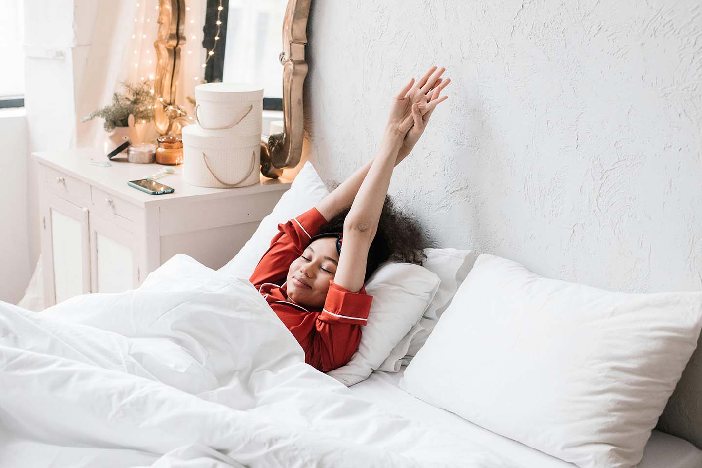 woman in red pajamas waking up in bed and stretching