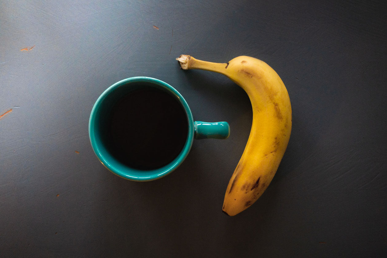 yellow banana beside green ceramic mug