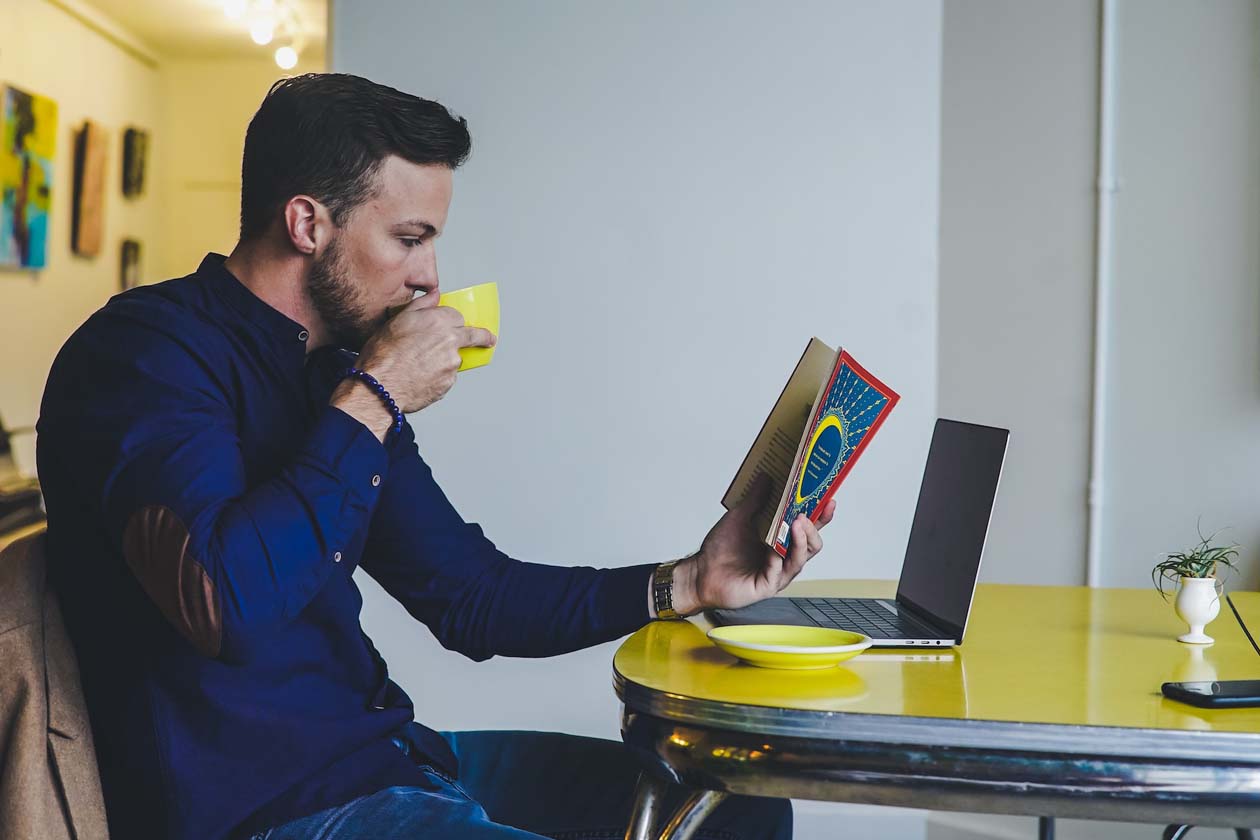 a man reading a book while drinking coffee