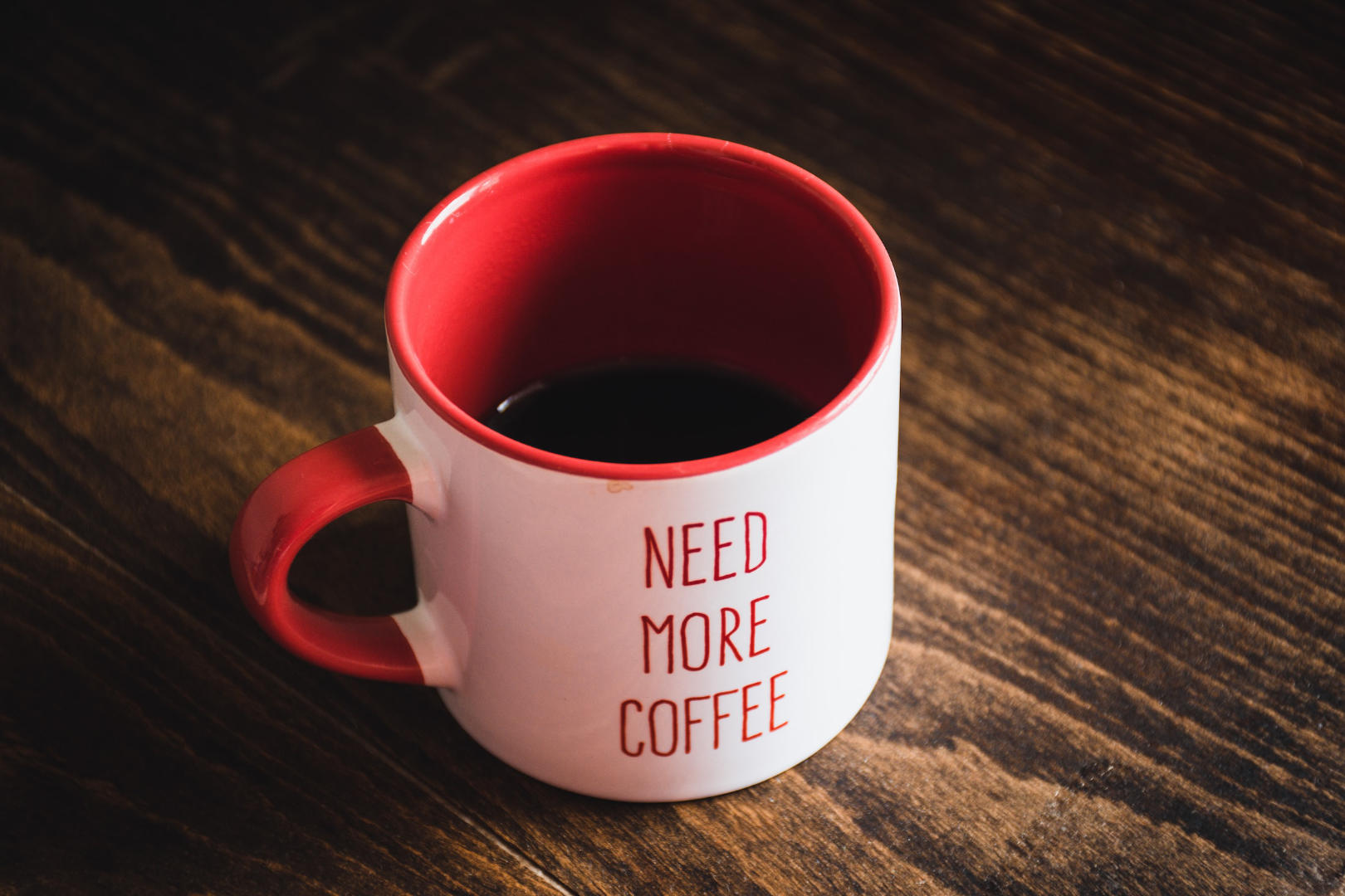 A half-filled cup with printed text saying need more coffee.