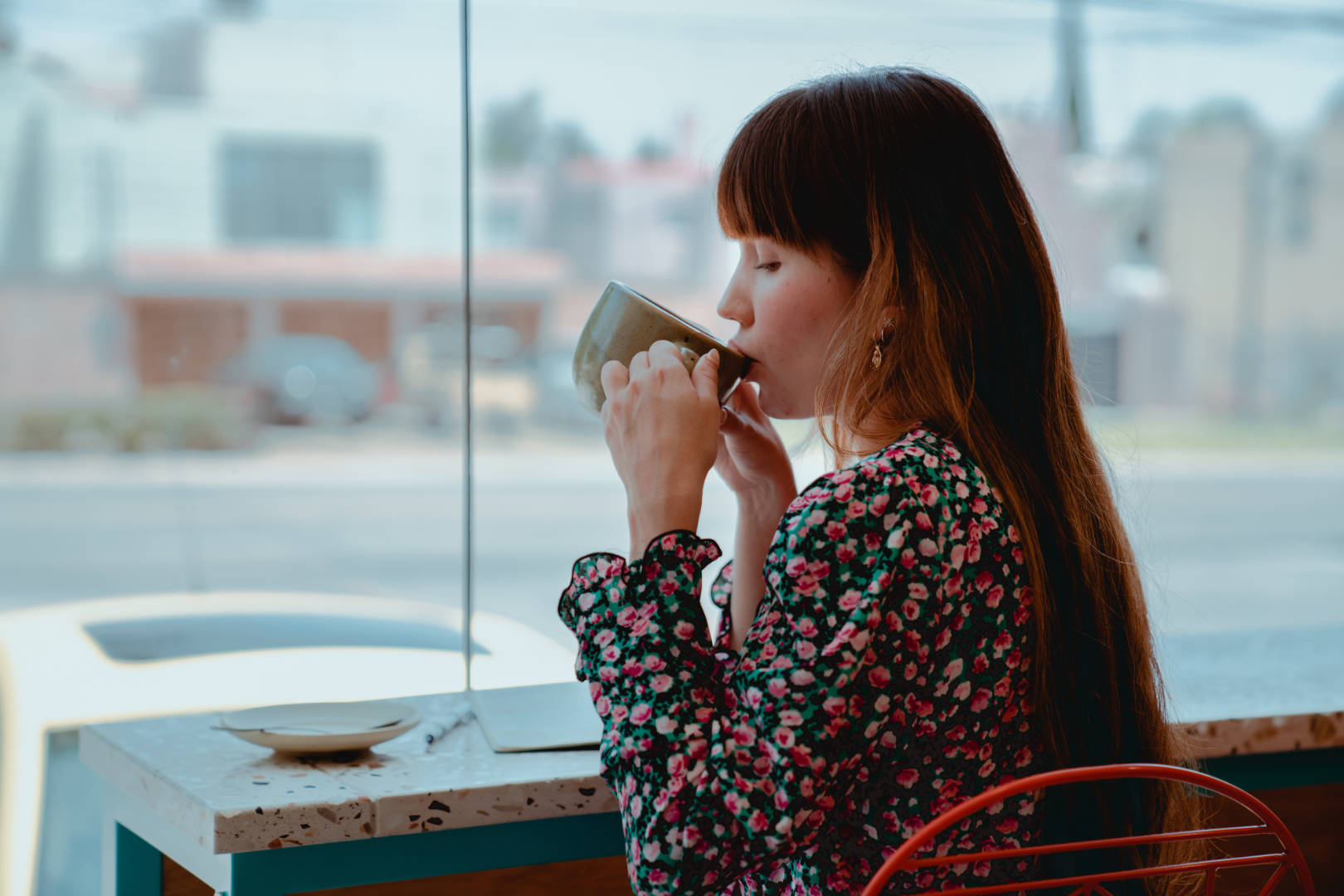 A young woman wearing a flowery dress while indulging in a cup of coffee in a cafe