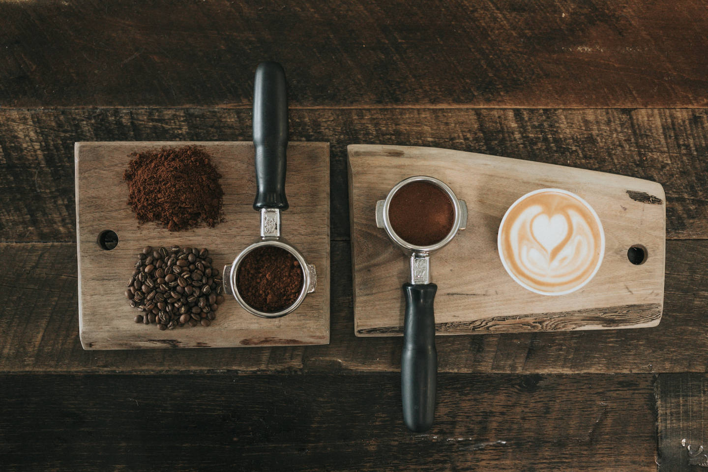 Two coffee portafilter filled with coffee in different grind size placed in a wooden board and surface.