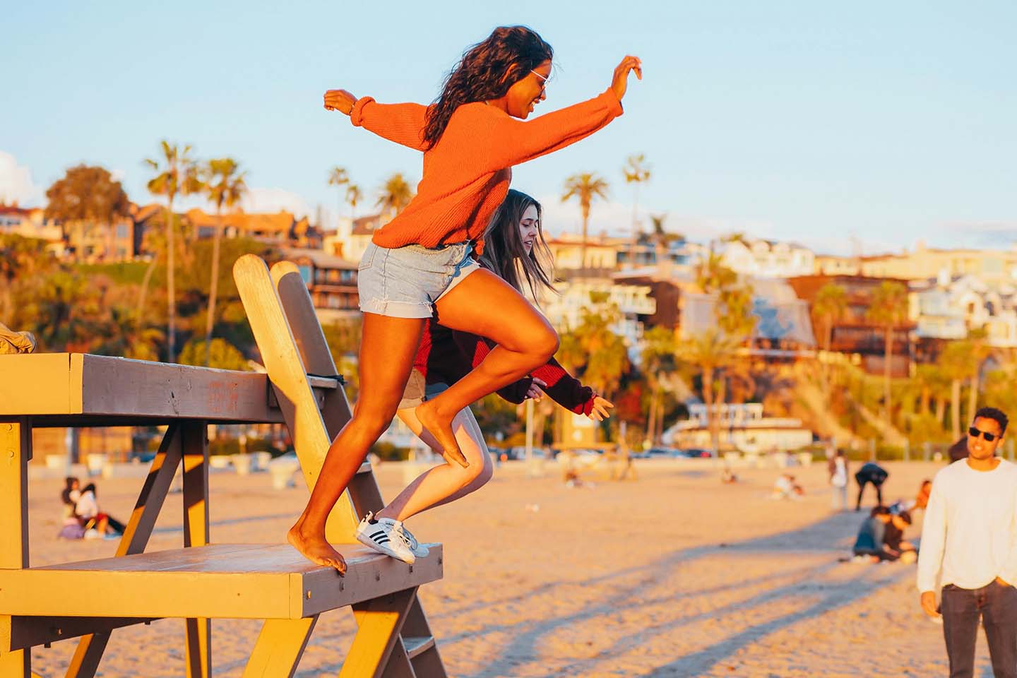 two women jumping off a platform onto a sandy beach