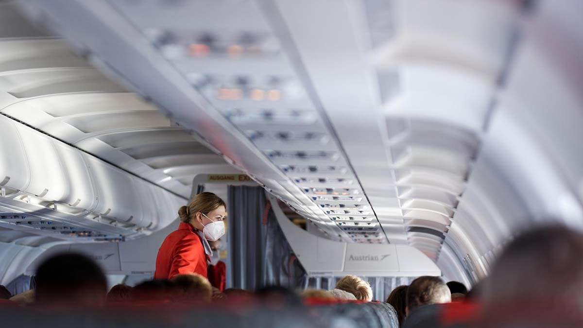 Stewardess speaking to a passenger in a plane cabin.