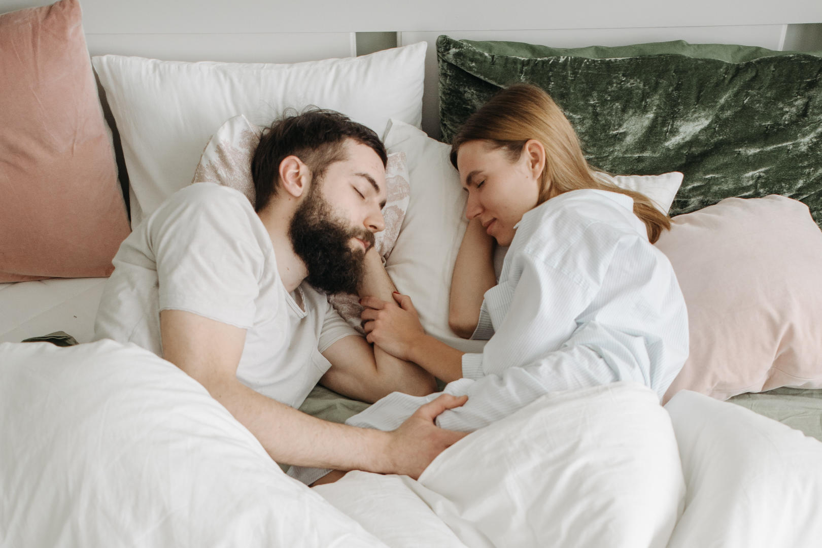 A couple sleeping facing and holding each other.