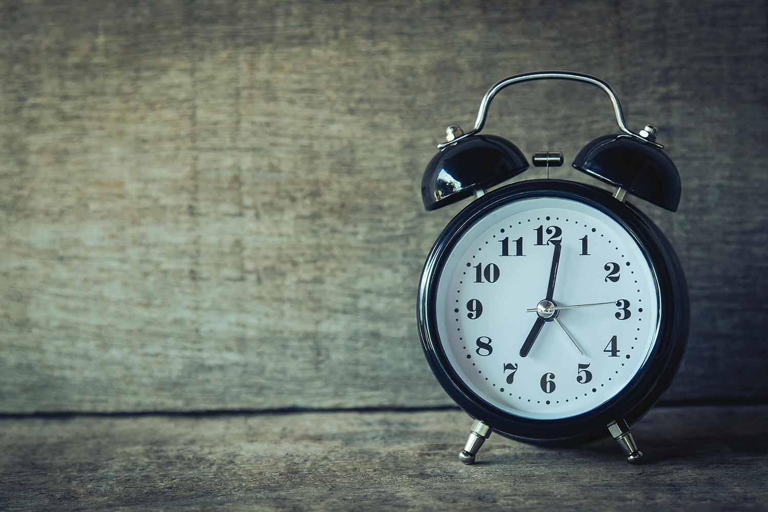 Old-fashioned alarm clock on a wooden surface
