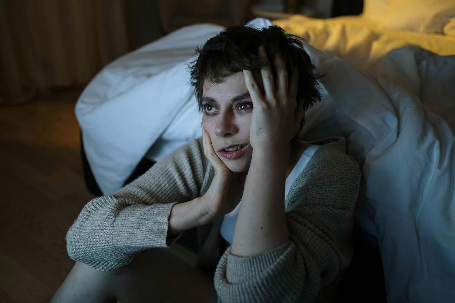 Exhausted and frustrated woman sitting by an unmade bed