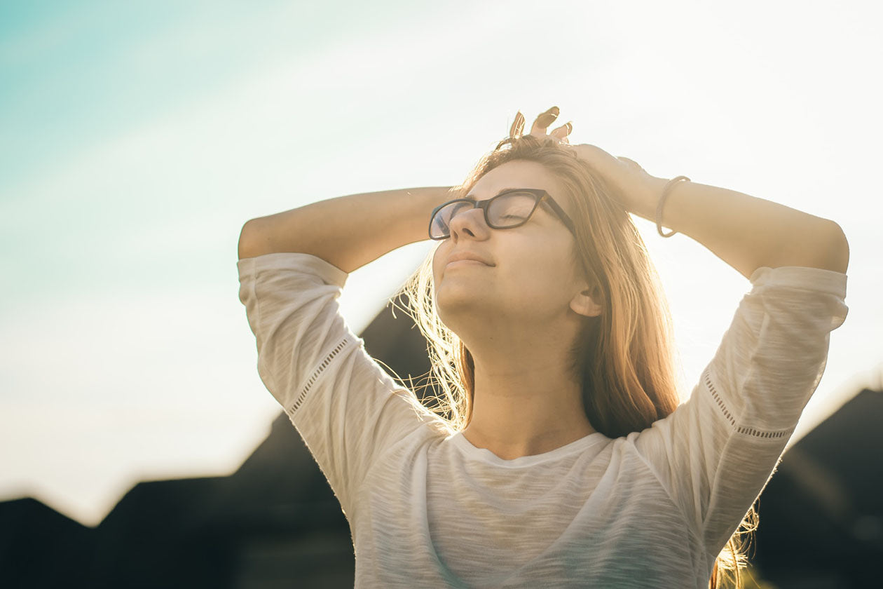 woman in white crew-neck T-shirt holding her head and smiling