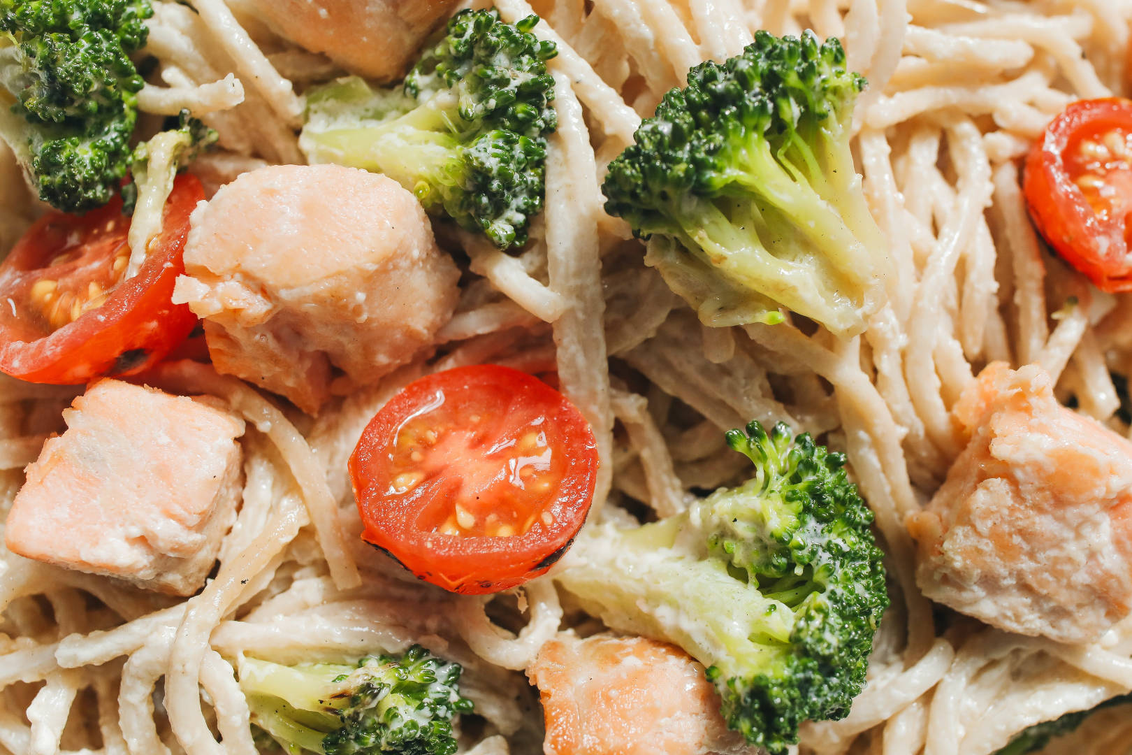 A white pasta with broccoli and tomatoes.