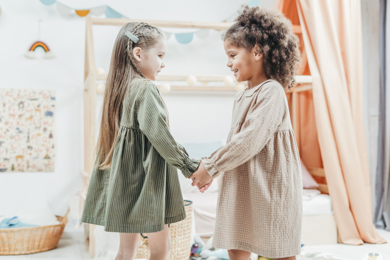 Two girls standing while playing in their bedroom