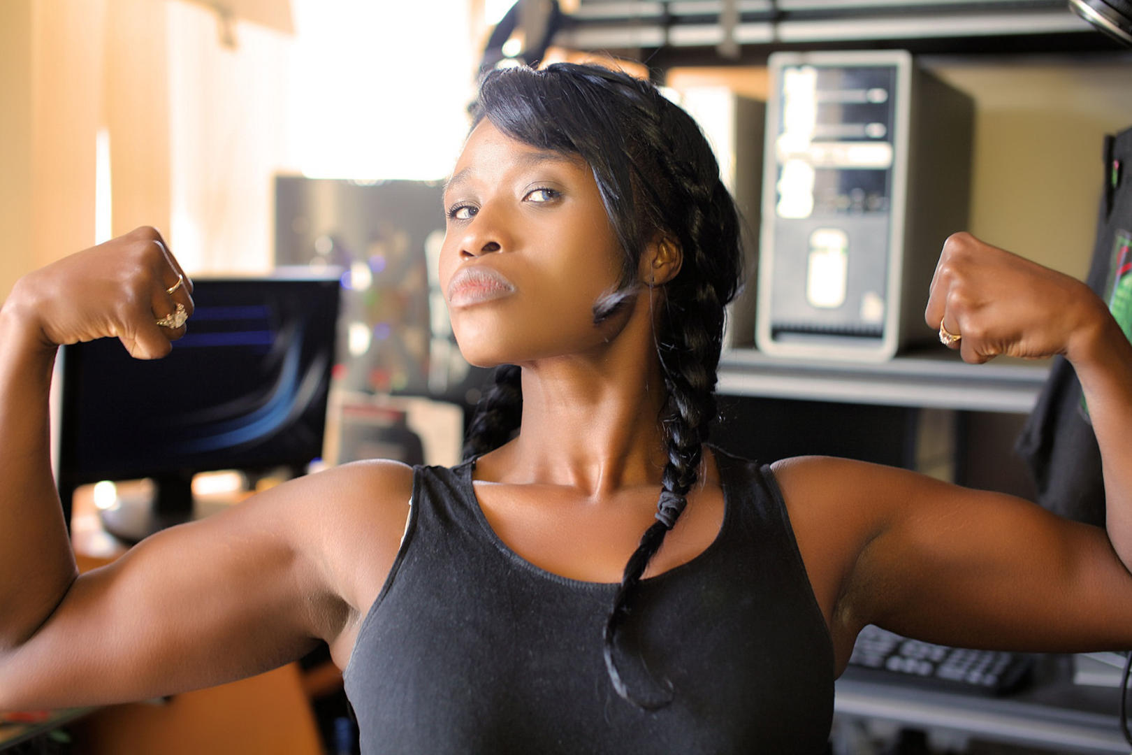 A black woman proudly flexing her biceps muscles.