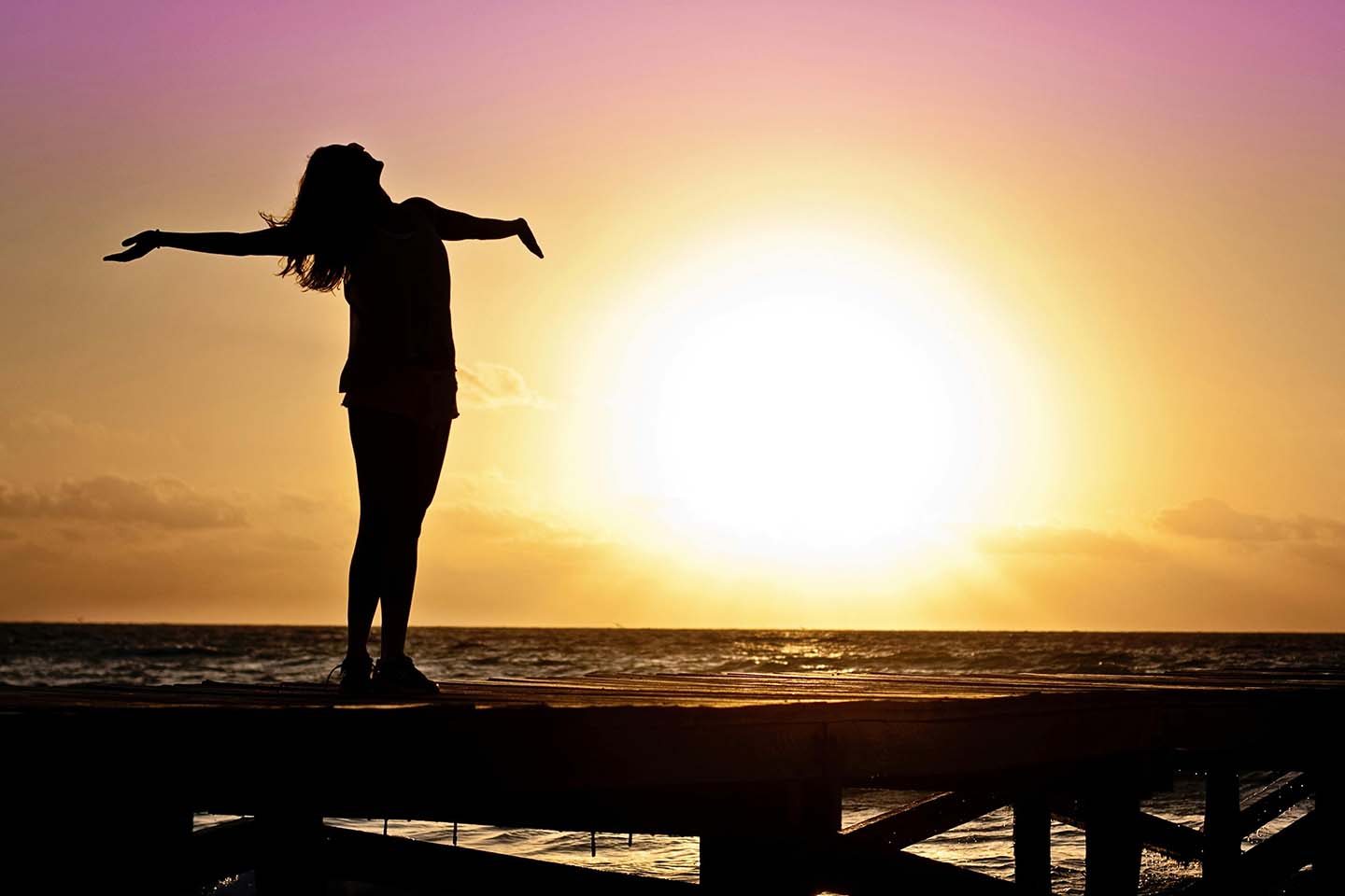 Woman with outstretched arms at sunrise