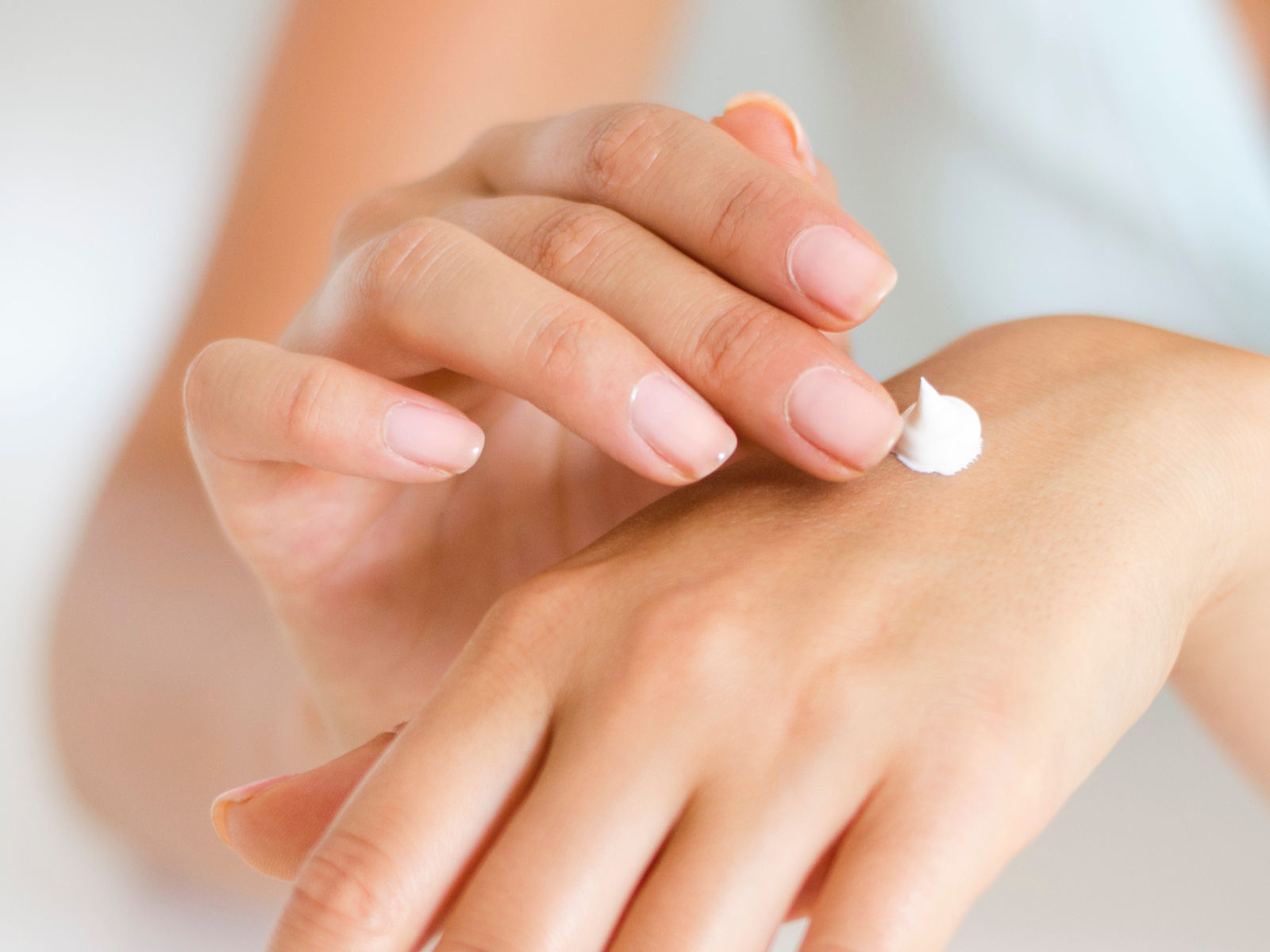 A woman applying a cream on her hands.