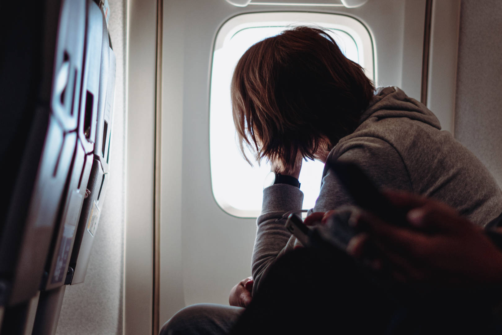 A seated flight passenger looks over the airplane window.