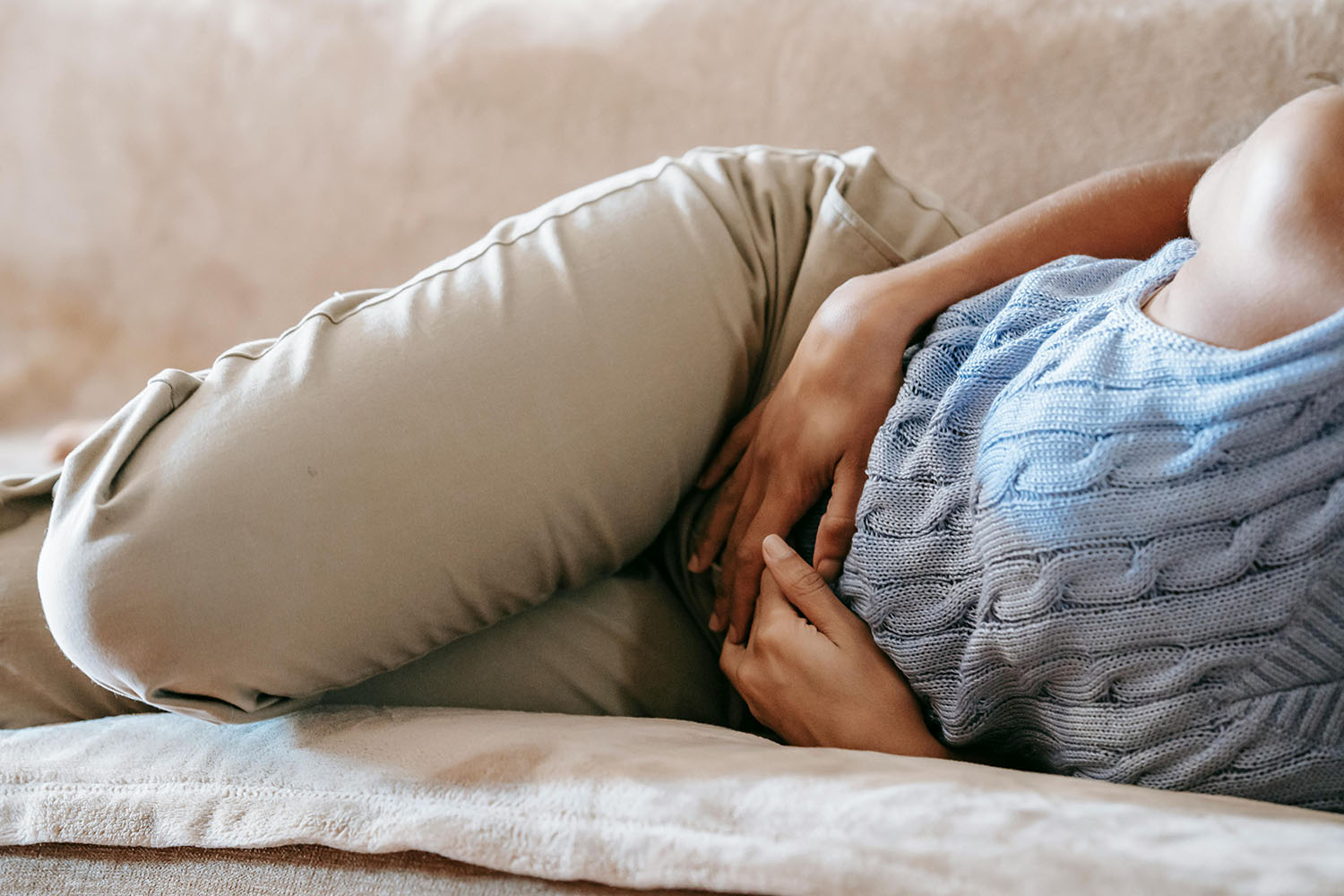 A woman lying on a couch holding her stomach