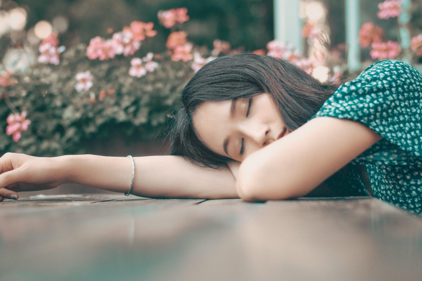 A young woman sleeping on a table outside.