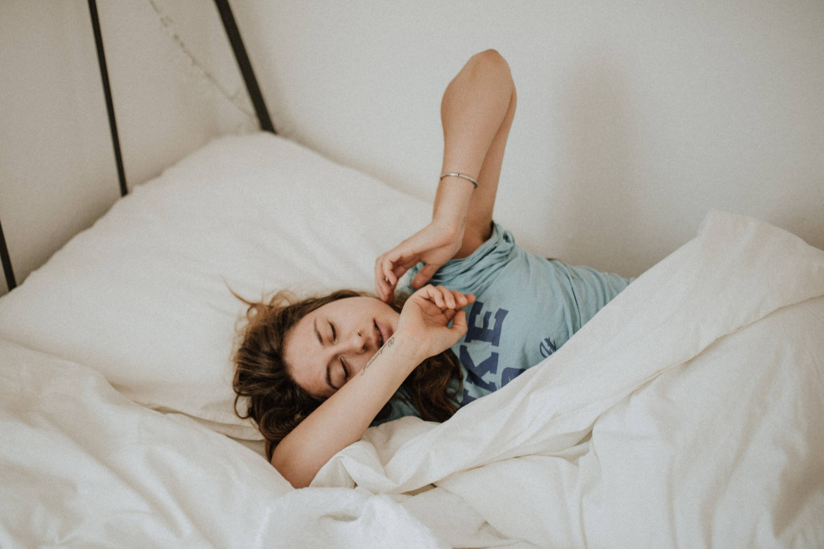 A woman sleeping in bed covered in a white blanket.