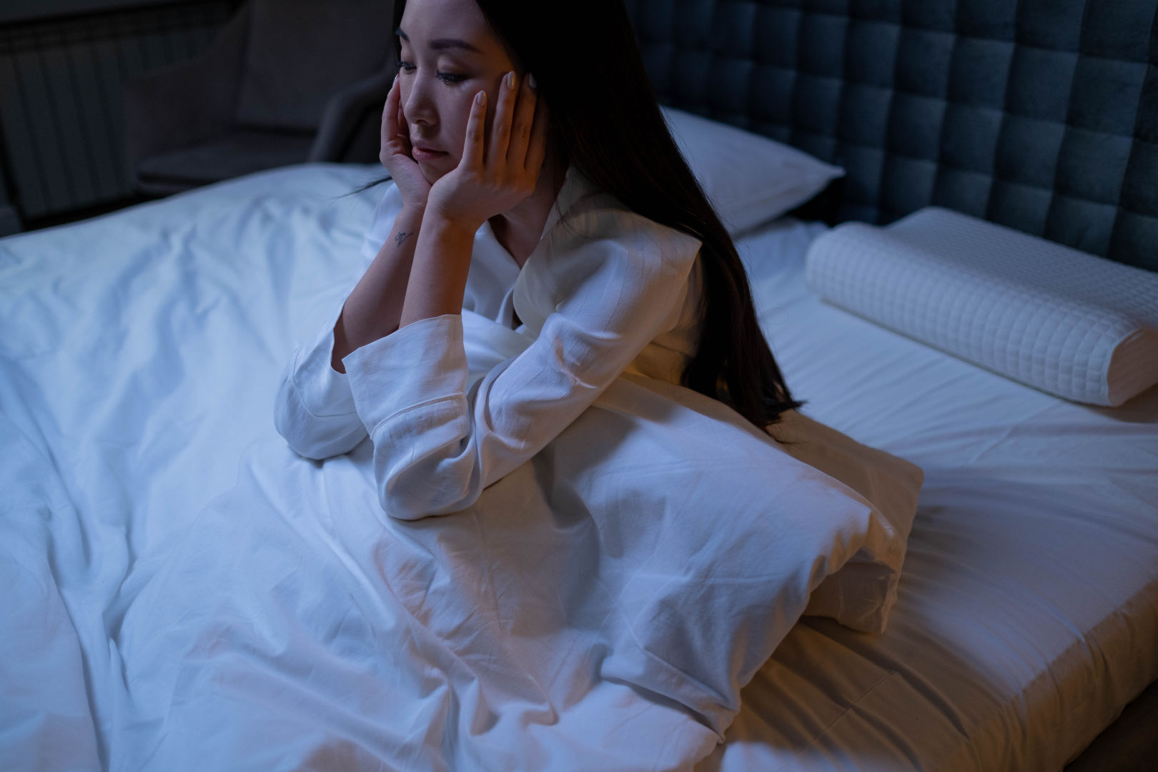 A woman sitting on her bed stressed and couldn't sleep.